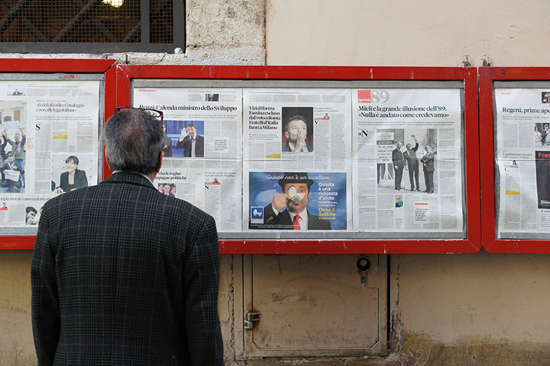 Man reading a news from newspapers hanging on the wall